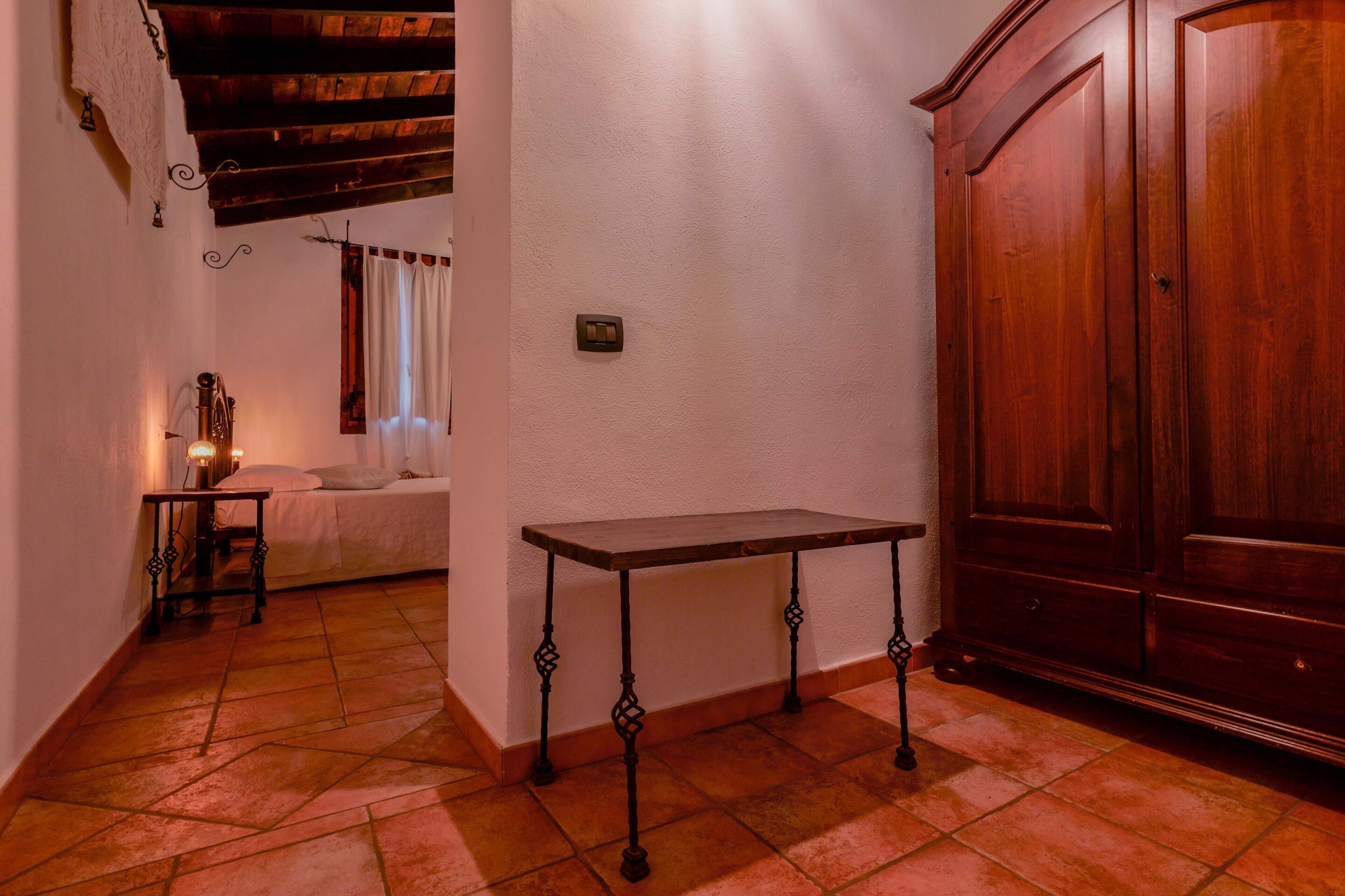 Un pasillo estrecho con una mesa de madera, una cama y un armario.