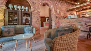 A cozy interior with a stone archway, wicker furniture, and a bar area with shelves of bottles. - Hotel Il Monastero (Quartu Sant'Elena)