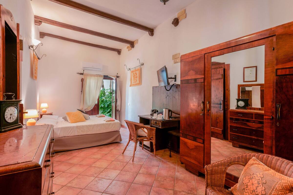 Une chambre à coucher comprenant un lit, un bureau, une chaise, une armoire et un miroir.