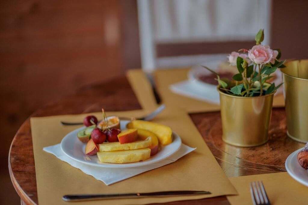 Una mesa con un plato de fruta y un jarrón pequeño con flores.