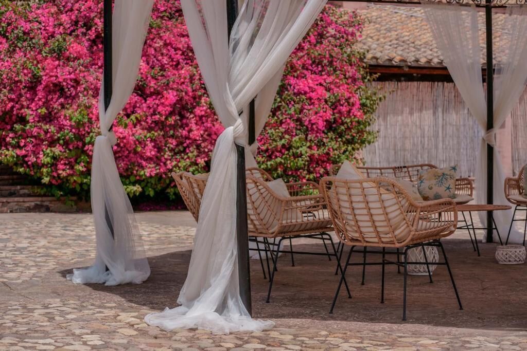 A covered outdoor seating area with wicker chairs and a white canopy.