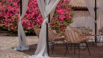 A covered outdoor seating area with wicker chairs and a white canopy.