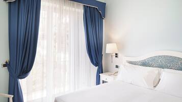 Une chambre d’hôtel avec un lit, une table de chevet, une lampe et des rideaux.