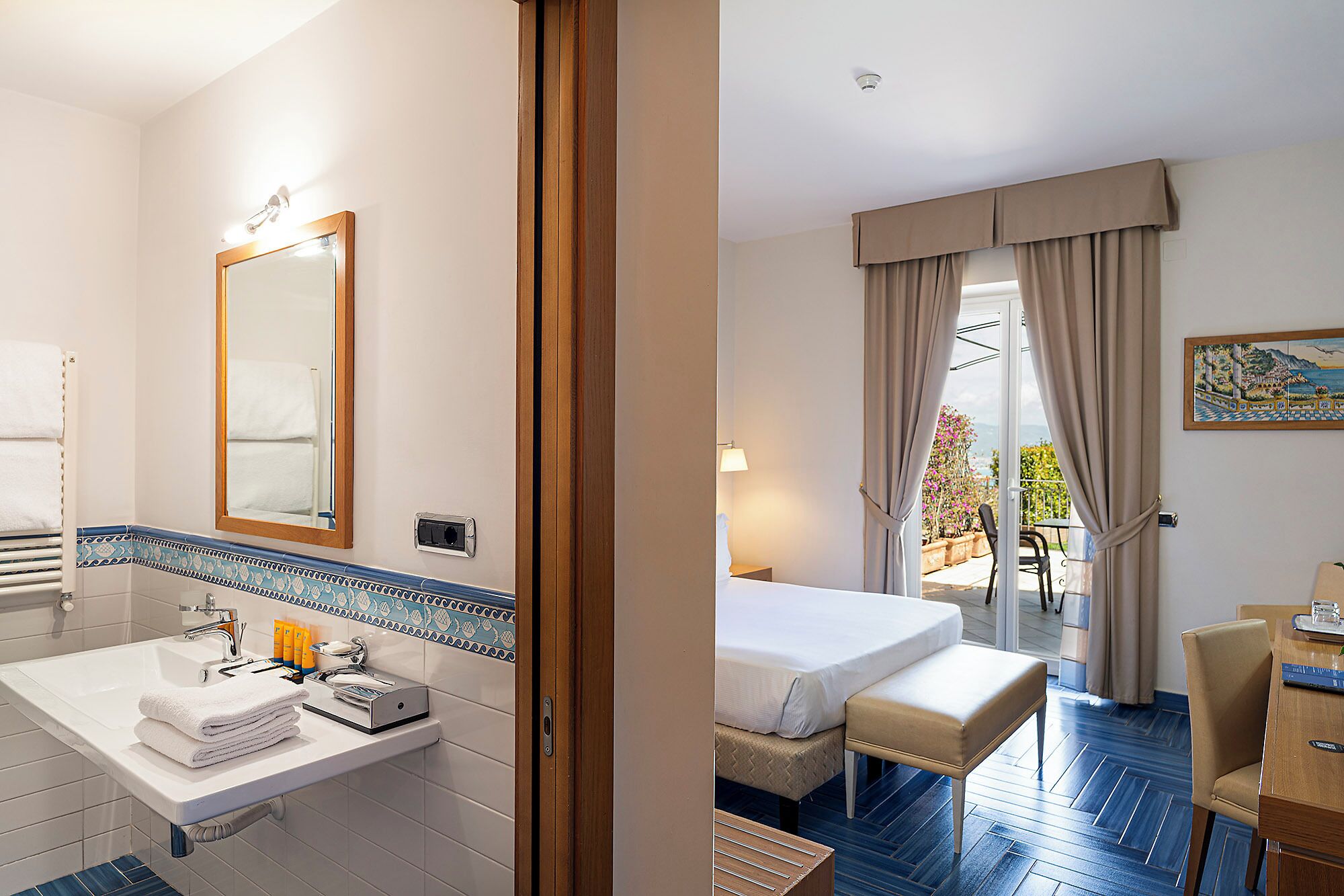 Habitación de hotel con baño, cama, escritorio y vista al exterior.