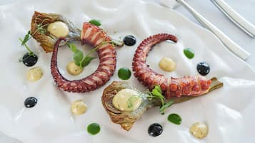A white plate with octopus tentacles and small green leaves.