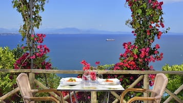 A table set for two with a view of the sea and mountains in the background.
