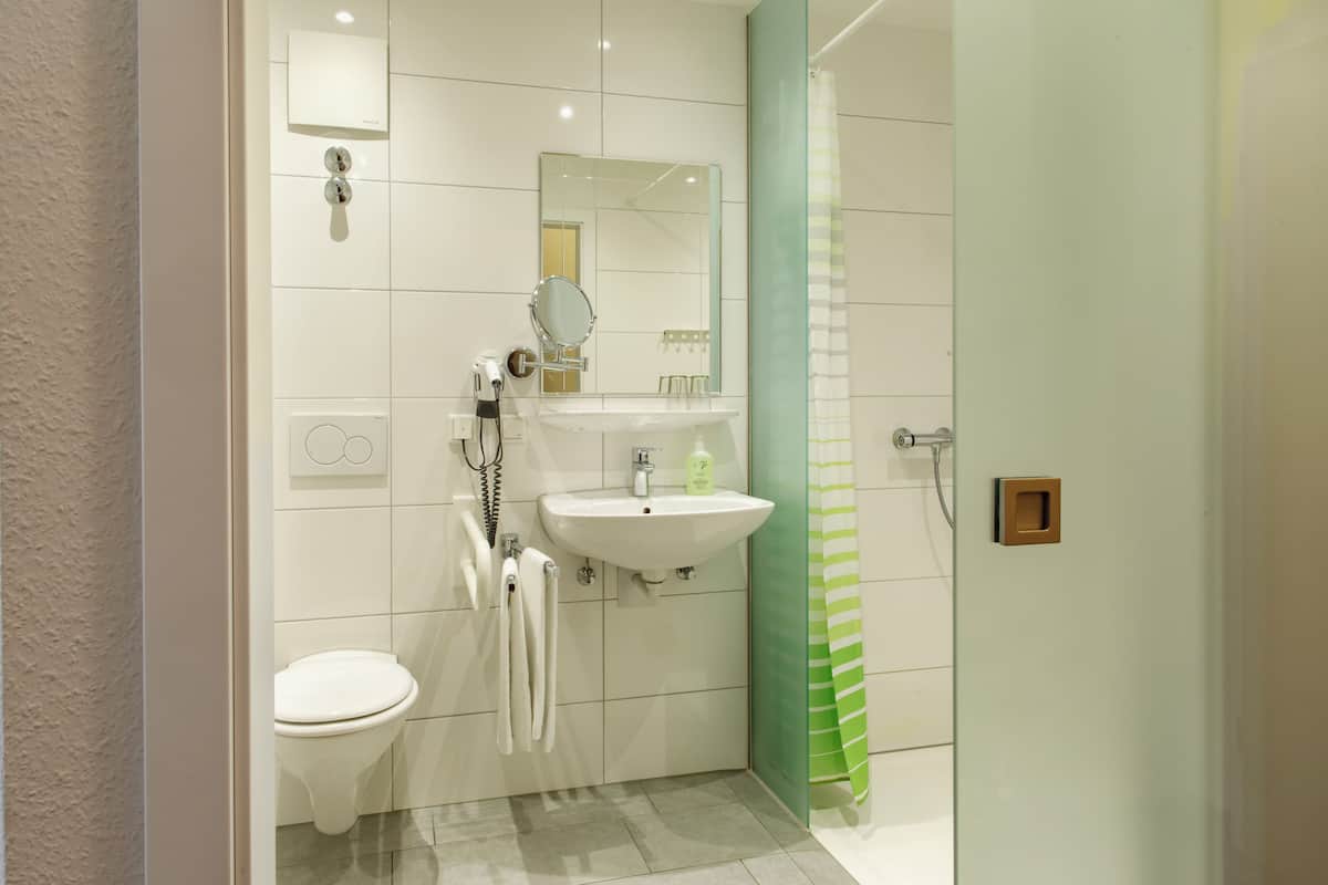Een moderne badkamer met toilet, wastafel en douche.
