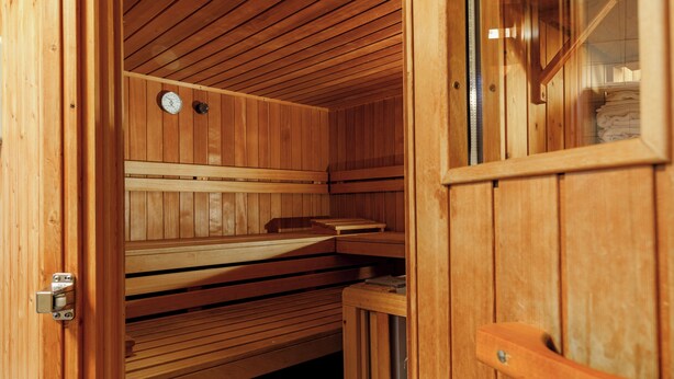 Un sauna en bois, avec des bancs et une porte.
