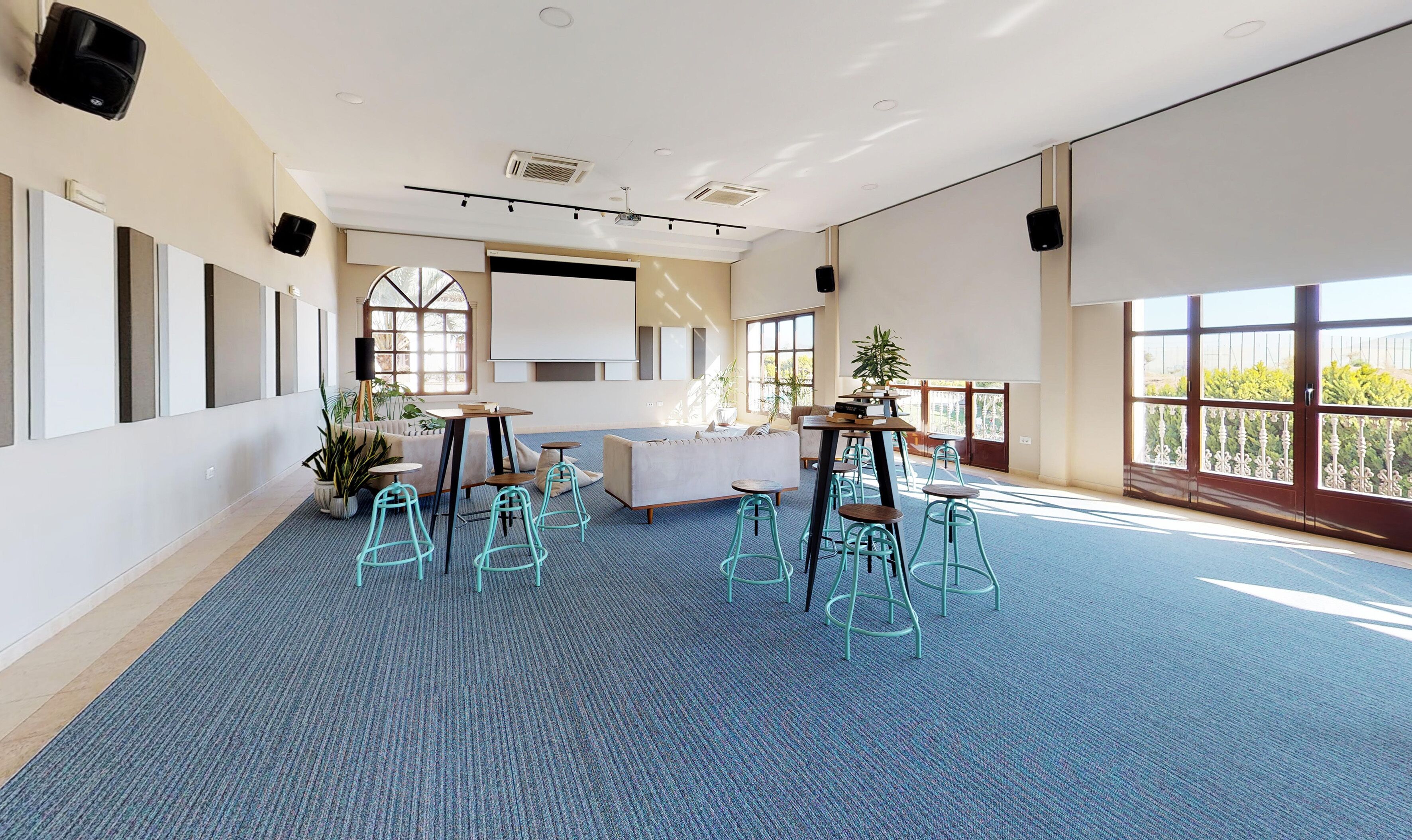 A spacious room with a large window, a sofa, a coffee table, and several chairs.