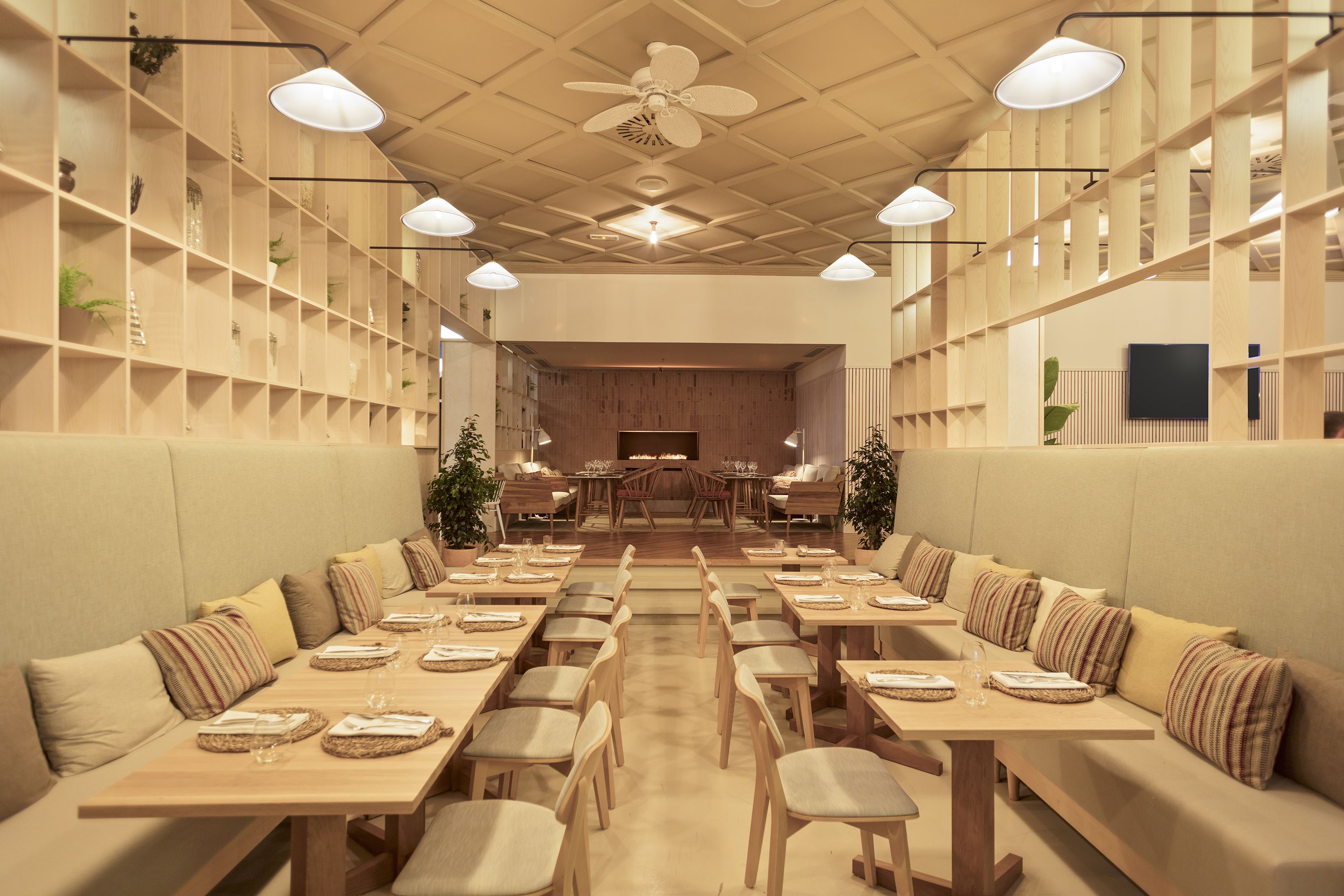 A spacious dining area with high tables and cushioned seating, a ceiling fan, and pendant lighting.