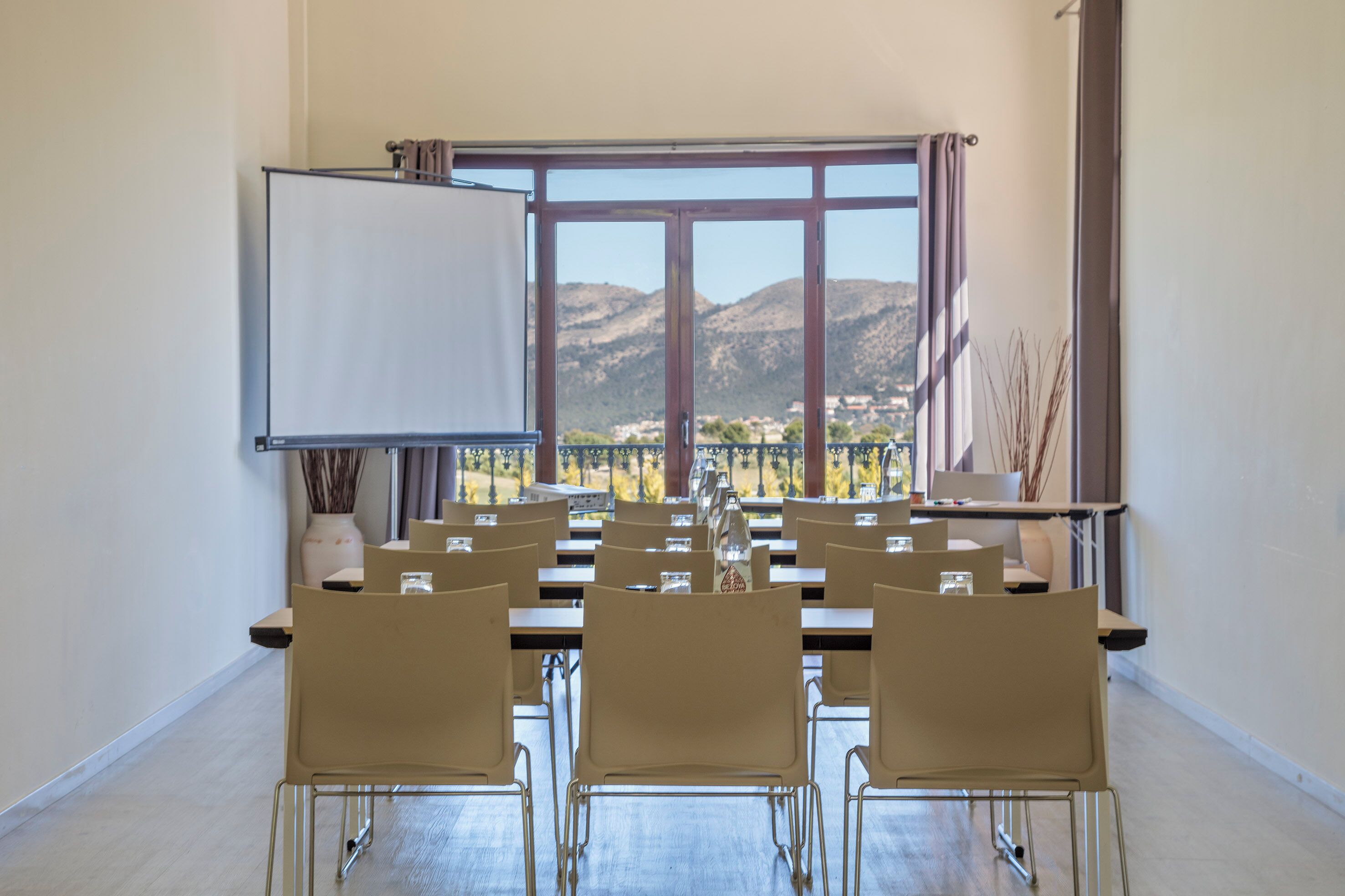Un salón de conferencias con un amplio ventanal, una pizarra y varias sillas dispuestas alrededor de una mesa.