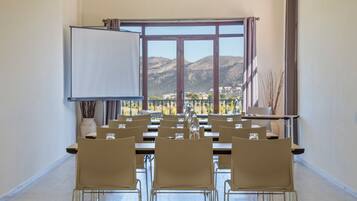 Un salón de conferencias con un amplio ventanal, una pizarra y varias sillas dispuestas alrededor de una mesa.