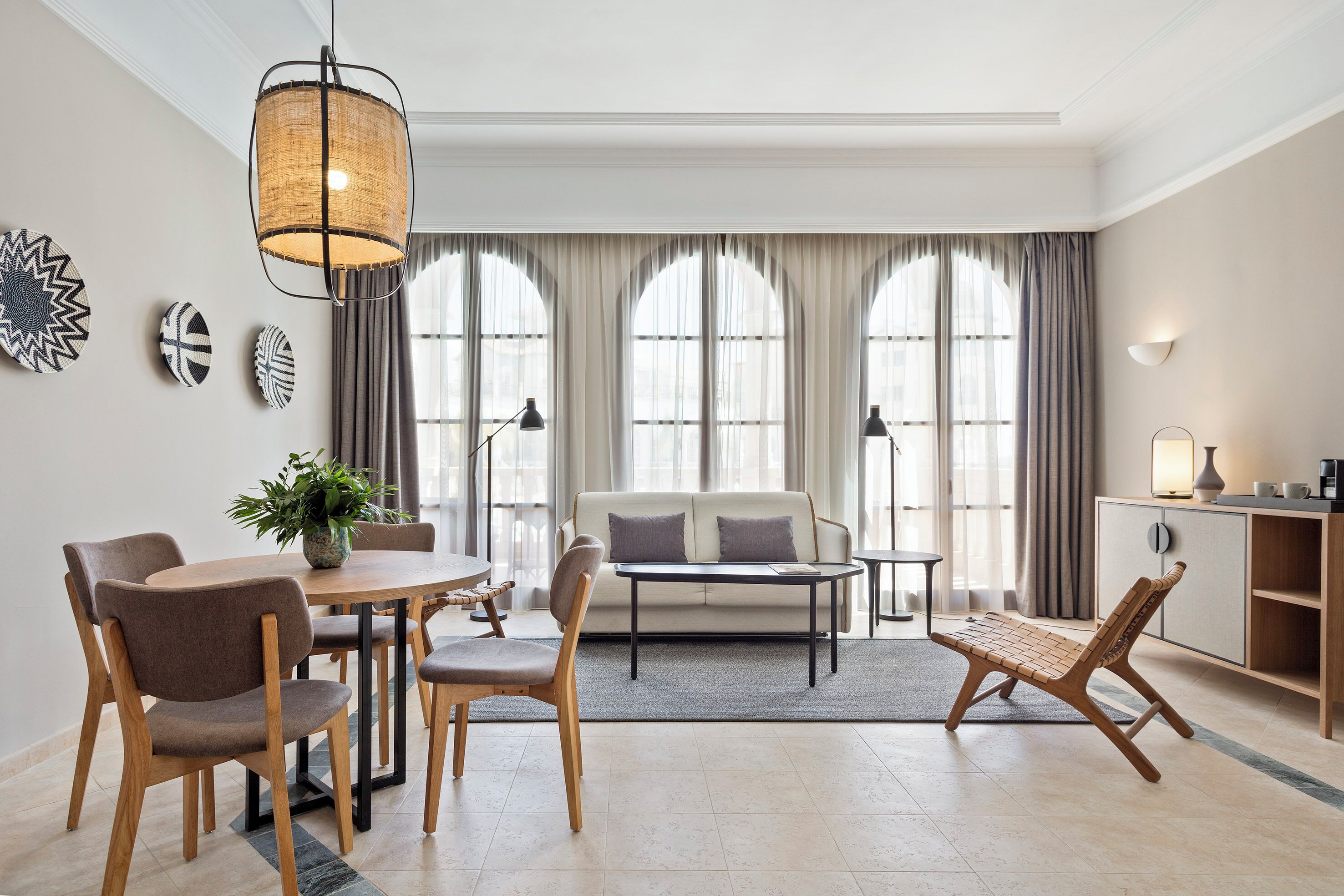 En moderne stue med spiseplads, der indeholder en sofa, stole, et sofabord og en lampe.