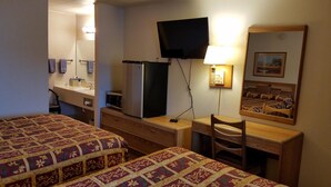 Une chambre d’hôtel avec deux lits, un bureau, une chaise, une télévision, un miroir et une fenêtre.