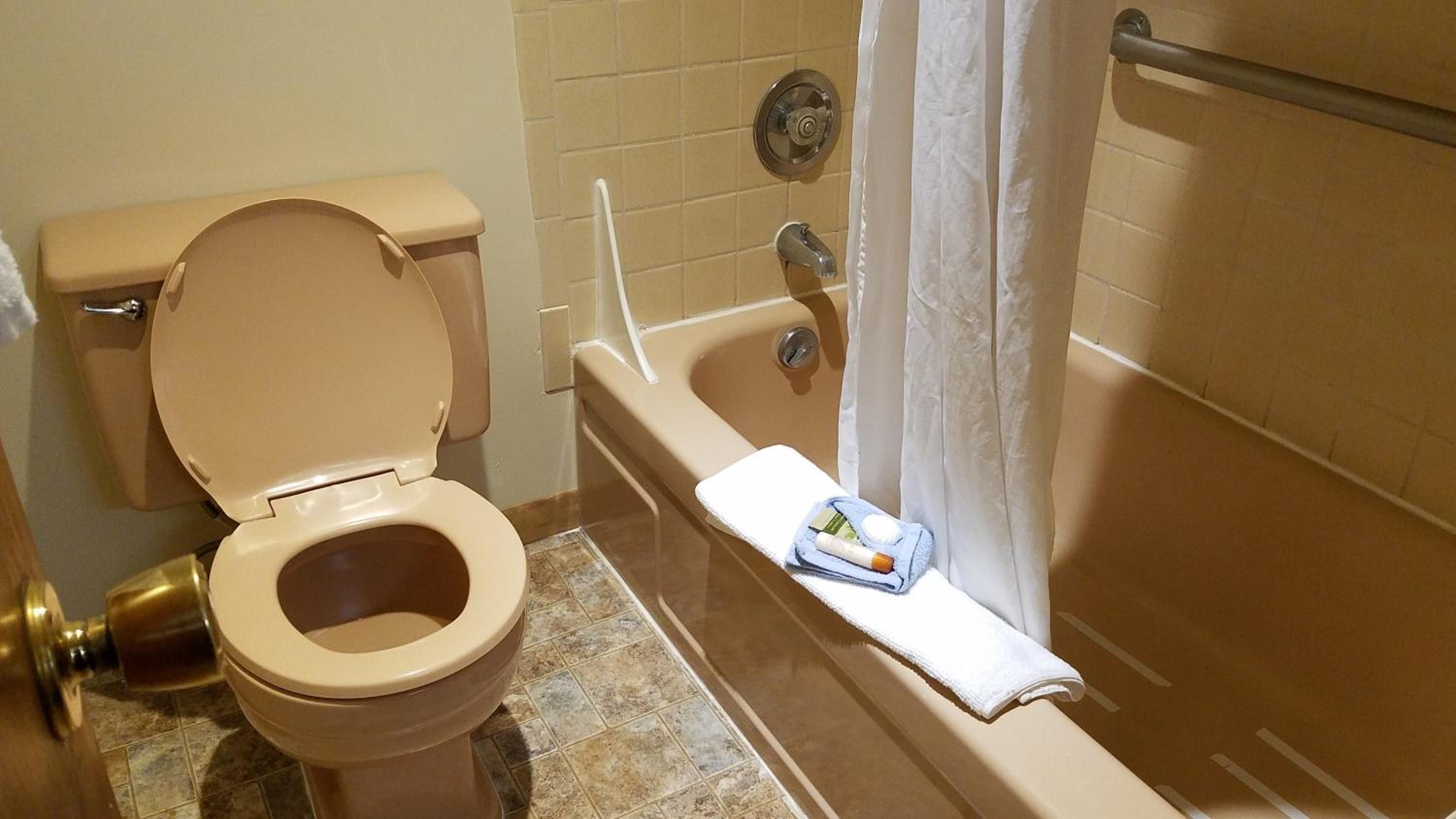 Un baño con inodoro, bañera y cortina de ducha.