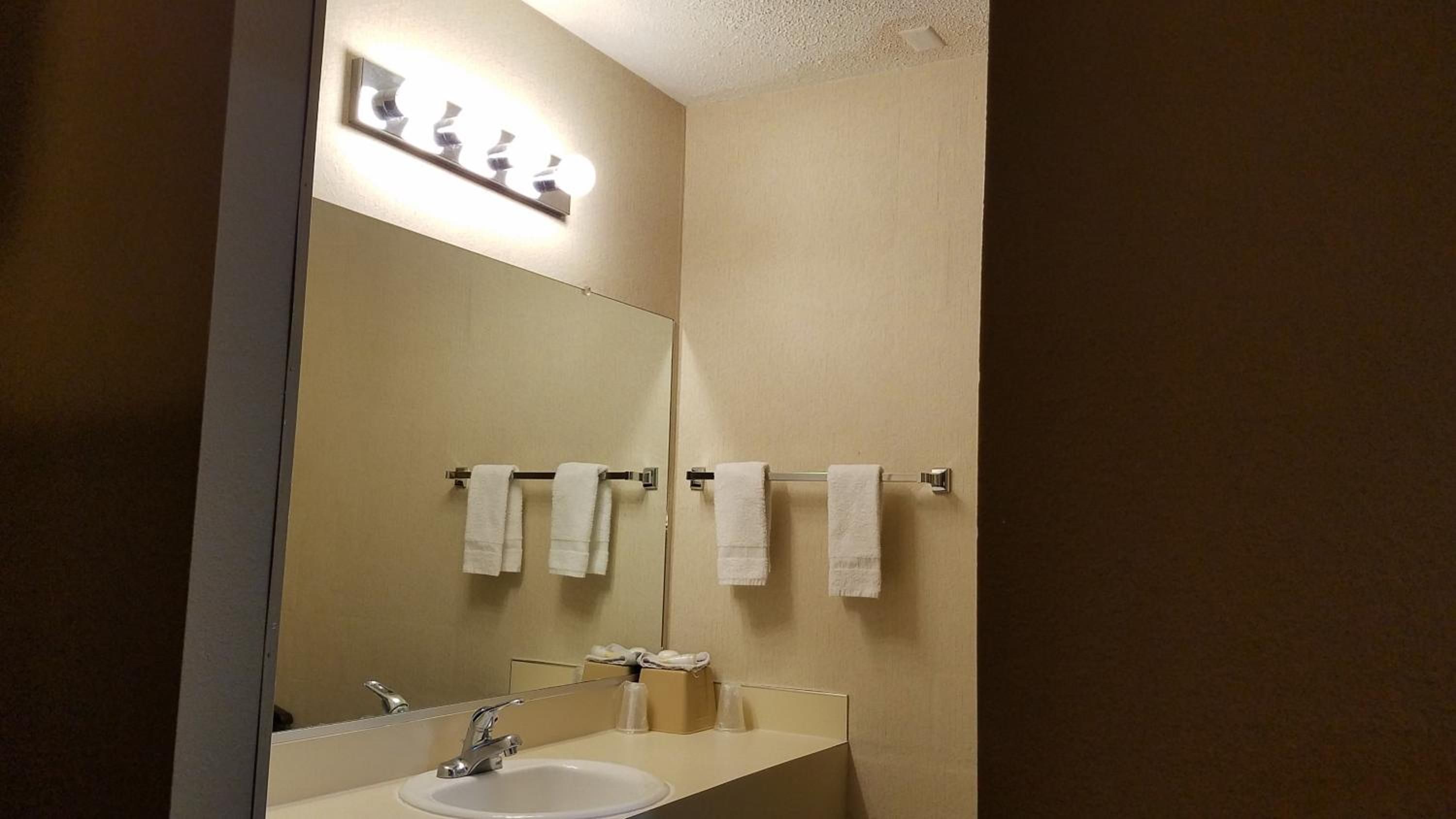 Un baño con lavamanos, espejo y perchero para toallas.