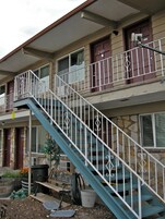 Un edificio de dos pisos con una escalera azul y barandales blancos.