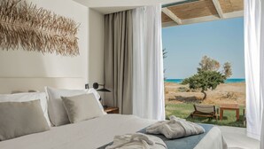 Ein Schlafzimmer mit Bett, Kissen, einem Nachttisch und Blick auf den Strand.
