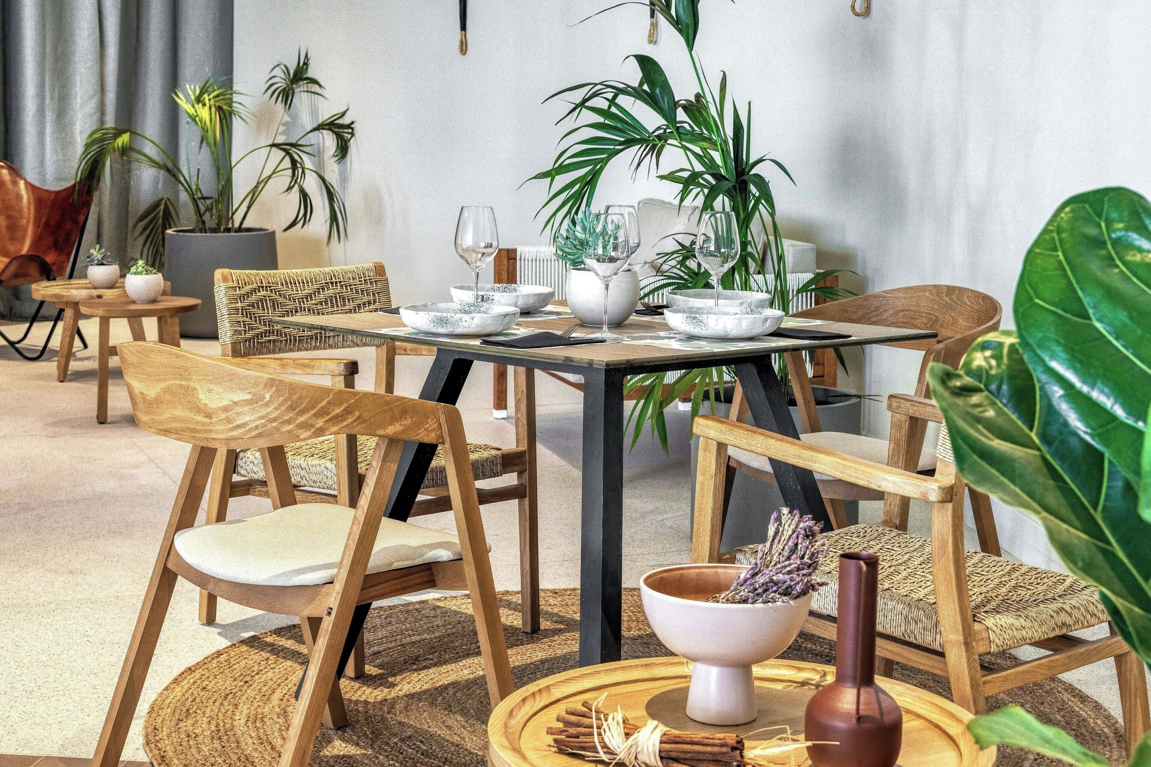 A dining area with a round table, wooden chairs, and potted plants.