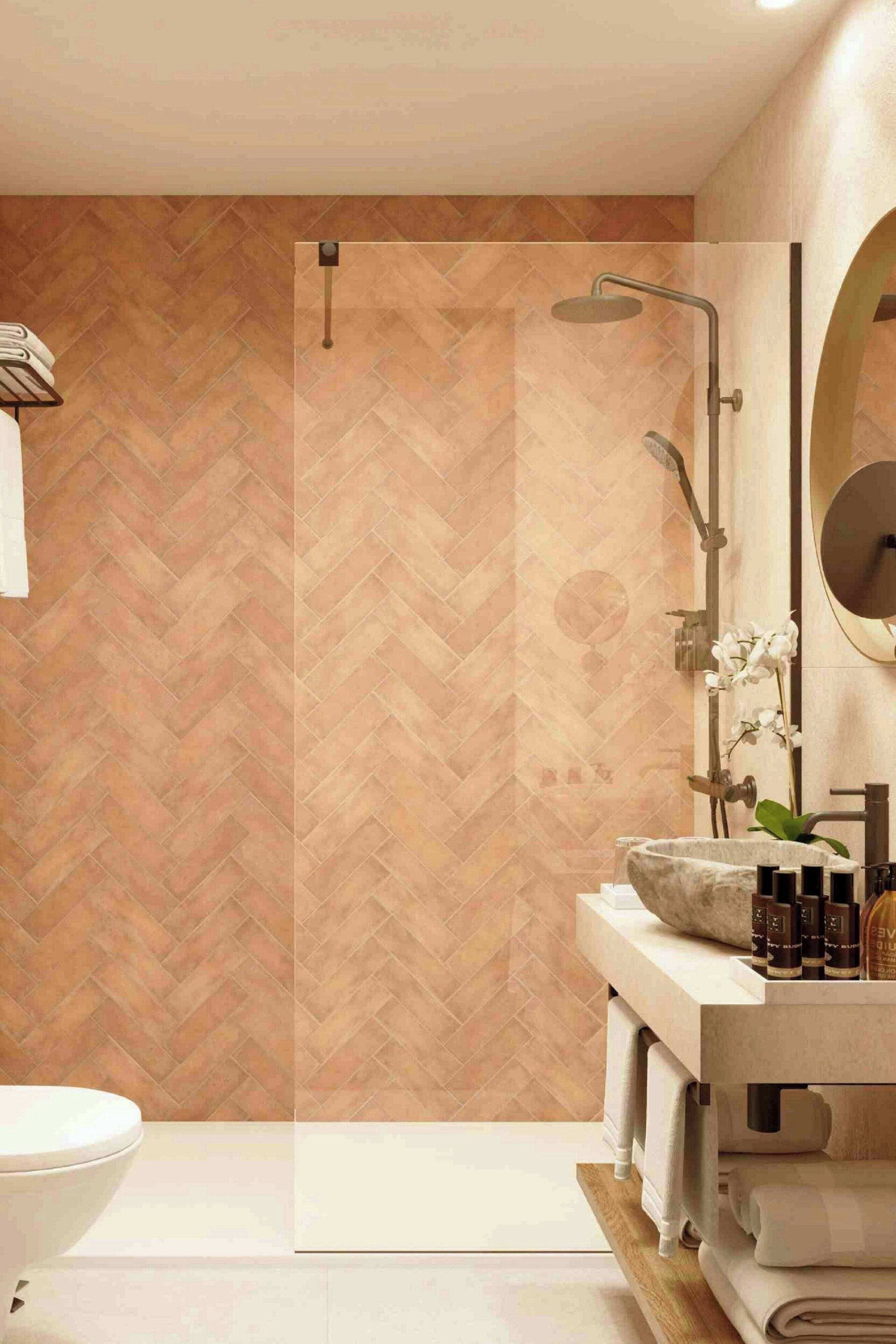 Une salle de bain moderne avec un mur orné d’un motif en chevrons, une baignoire sur pieds, un grand miroir et un meuble-lavabo avec des articles de toilette.