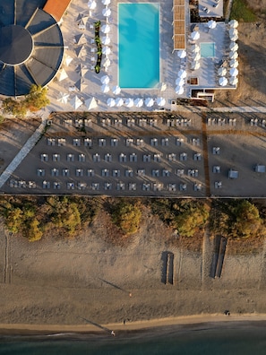 Una piscina al aire libre, sombrillas, sillones reclinables de piscina