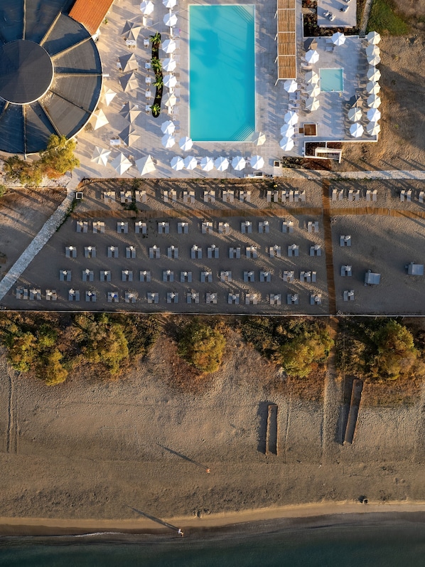 An aerial view of a resort with a swimming pool, sun loungers, and a beach area. - Domes Aulūs Zante - All Inclusive - Autograph Collection (Zakynthos)