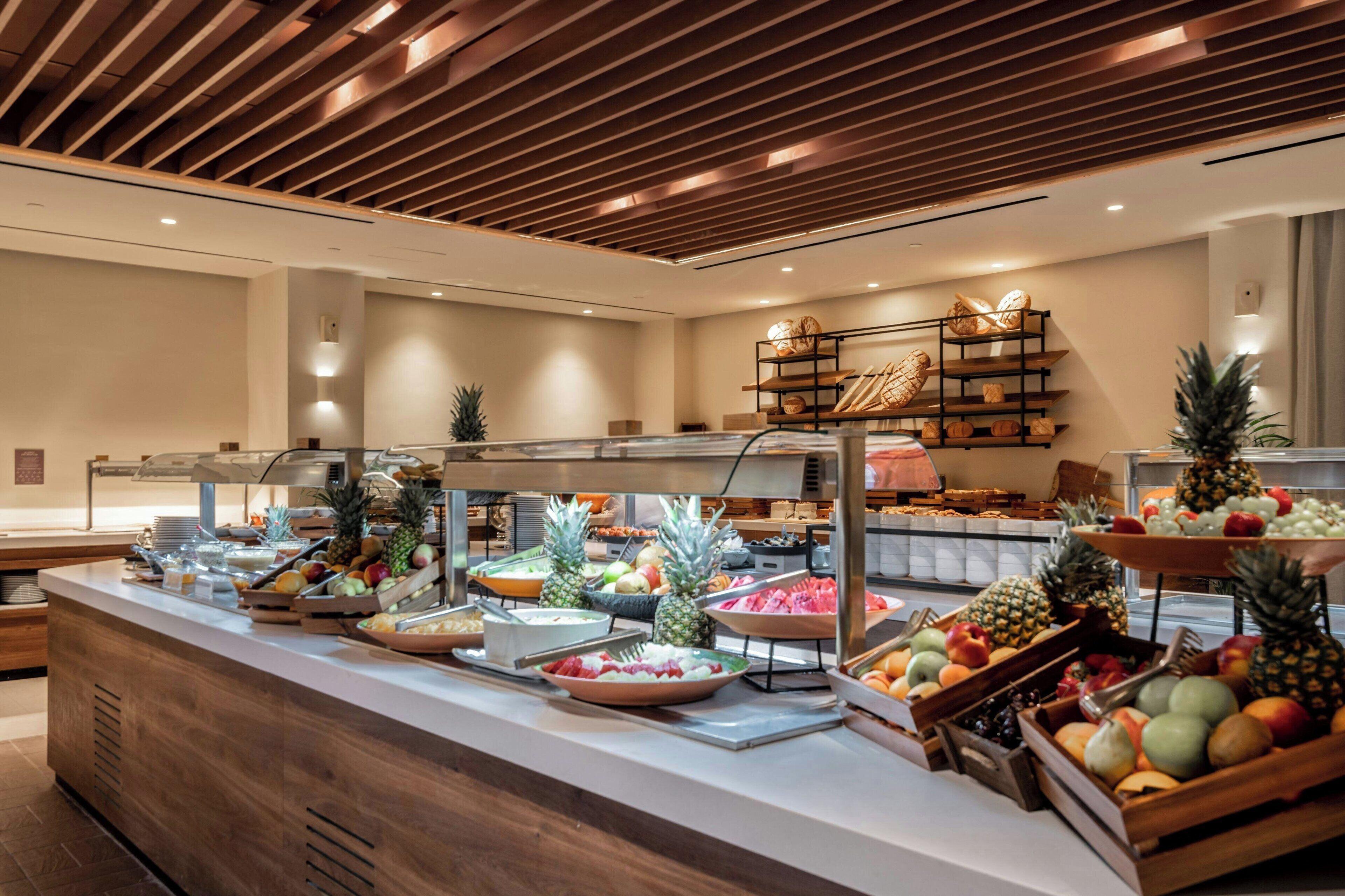 Uma área de buffet com diversas frutas e legumes dispostos em tigelas e cestos.
