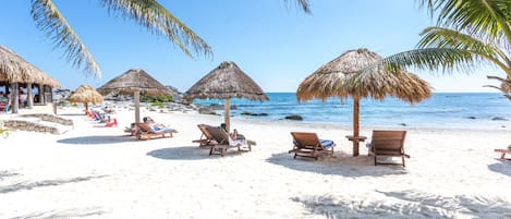 Am Strand, weißer Sandstrand, Sonnenschirme, Strandtücher