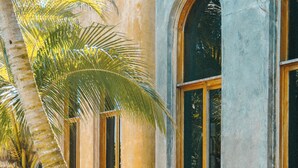 Um edifício com janelas em arco e uma palmeira em primeiro plano.