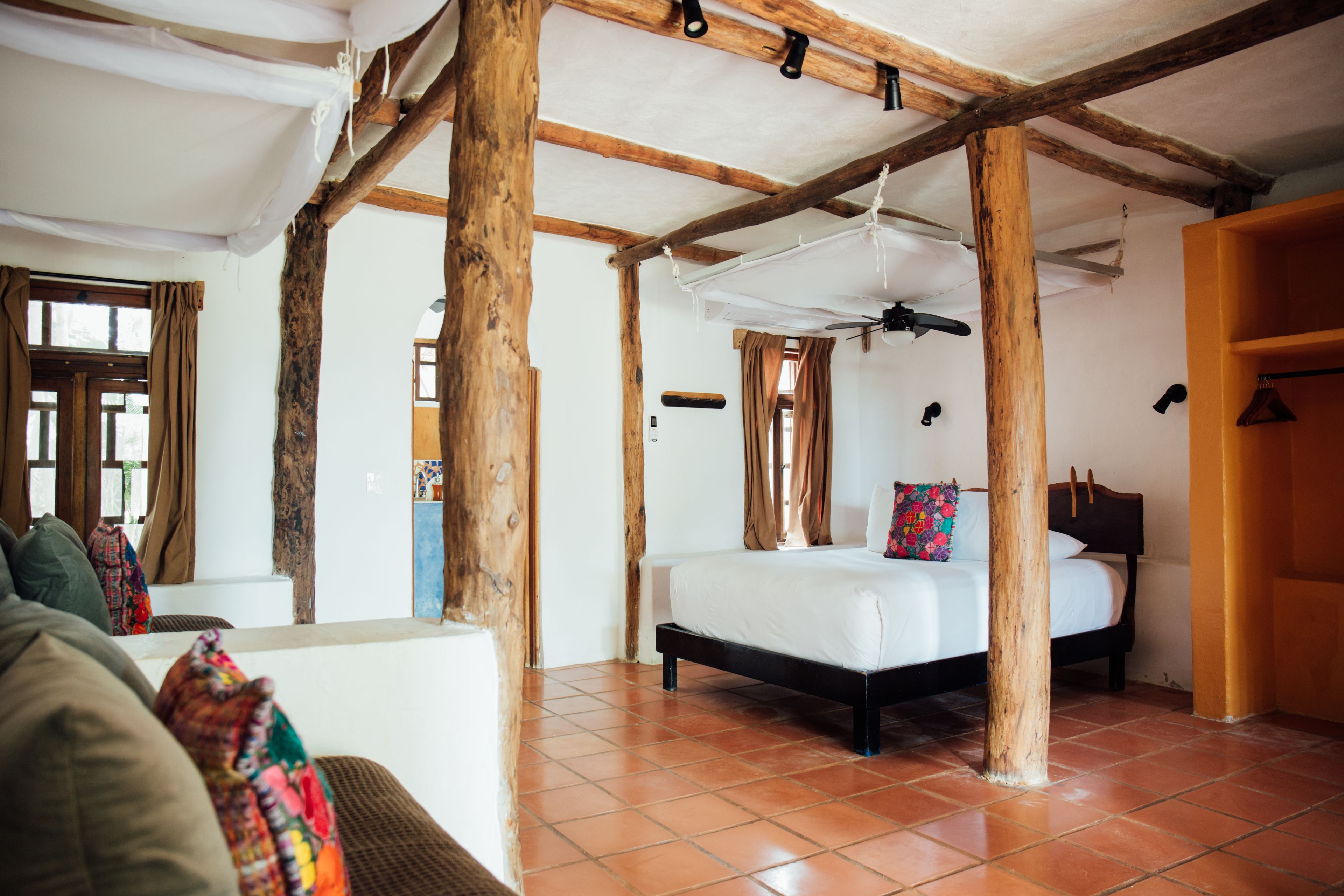 Un dormitorio con una cama, vigas de madera, un ventanal y una puerta.