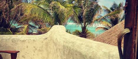 A balcony with a view of palm trees and a beach.