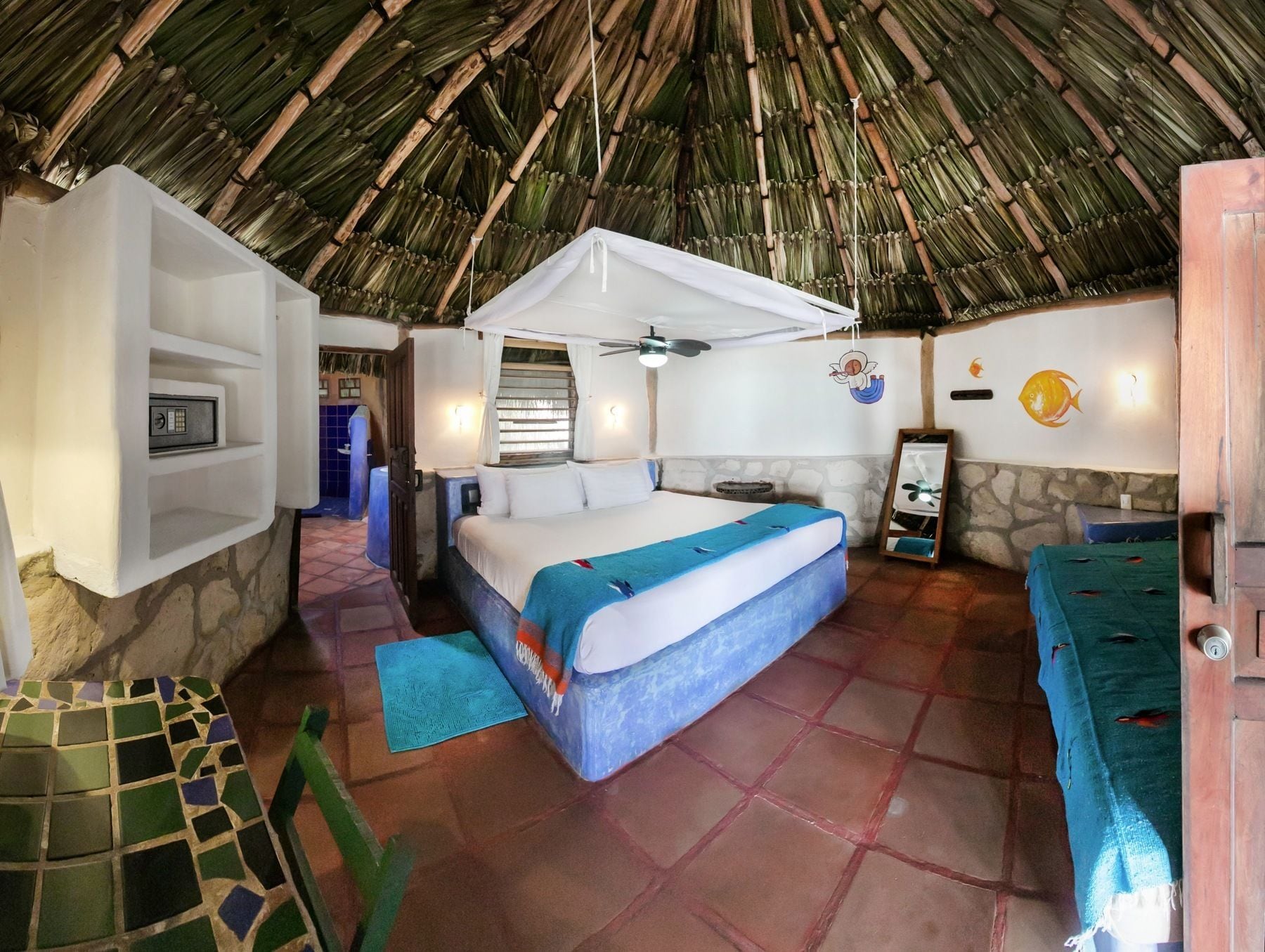 Ein Zimmer mit einem Bett, einem kleinen Tisch, einer Ablagefläche und einer Wand mit einem Fischgemälde.