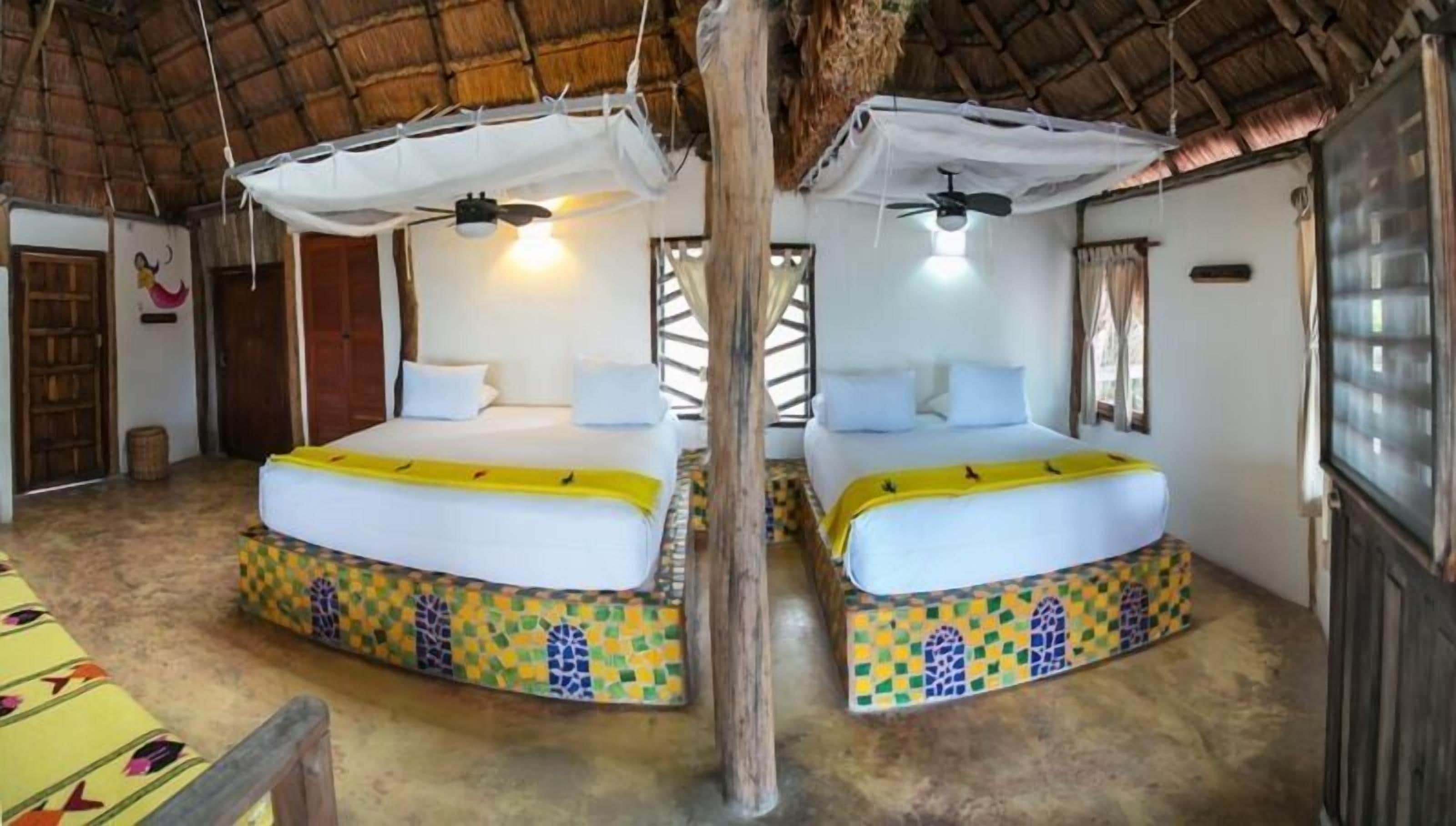 Ein Zimmer mit zwei Betten, jeweils mit Baldachin und farbenfrohem Mosaikfuß.