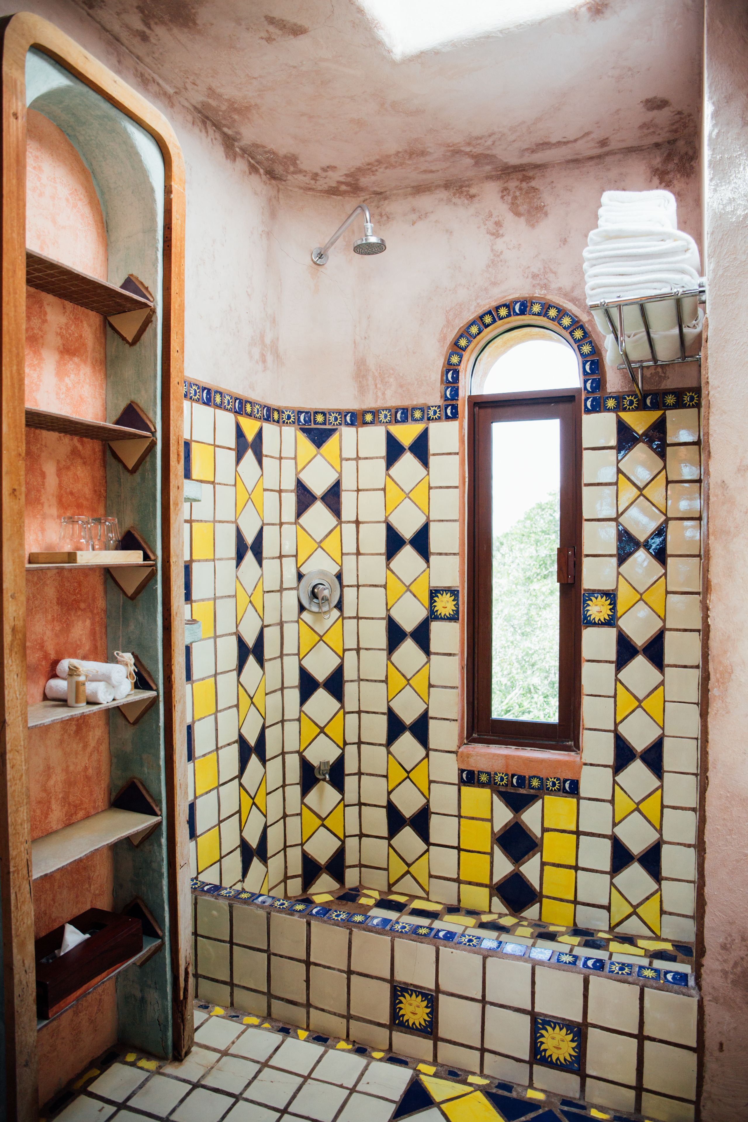 Un baño con pared de azulejos, ducha y ventana.