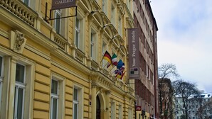 A historic building with ornate architecture, a snow-covered courtyard, and flags indicating it is a hotel. - Hotel Galileo Prague (Prague)