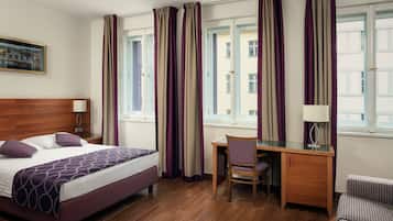 Una habitación de hotel con cama, escritorio, silla y cortinas.