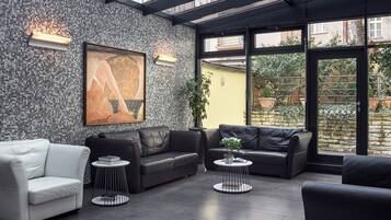 Et moderne loungeområde med en mosaikvæg, lædersofaer og et stort vindue med udsigt til det fri.
