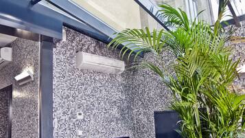 An office space with two desks, a potted plant, and a modern tiled wall.