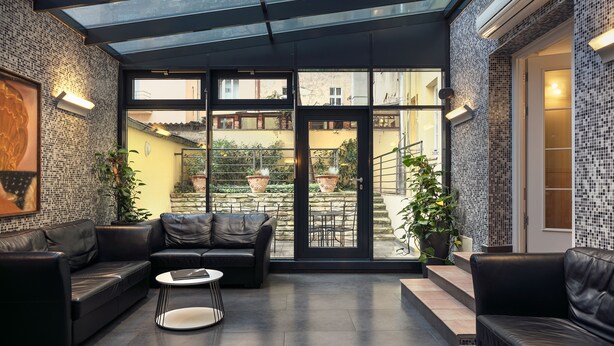A modern interior with leather sofas, a round table, and potted plants. - Hotel Galileo Prague (Prague)