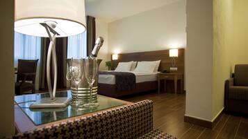 A hotel room with a bed, a nightstand, a lamp, and a seating area with a patterned sofa.