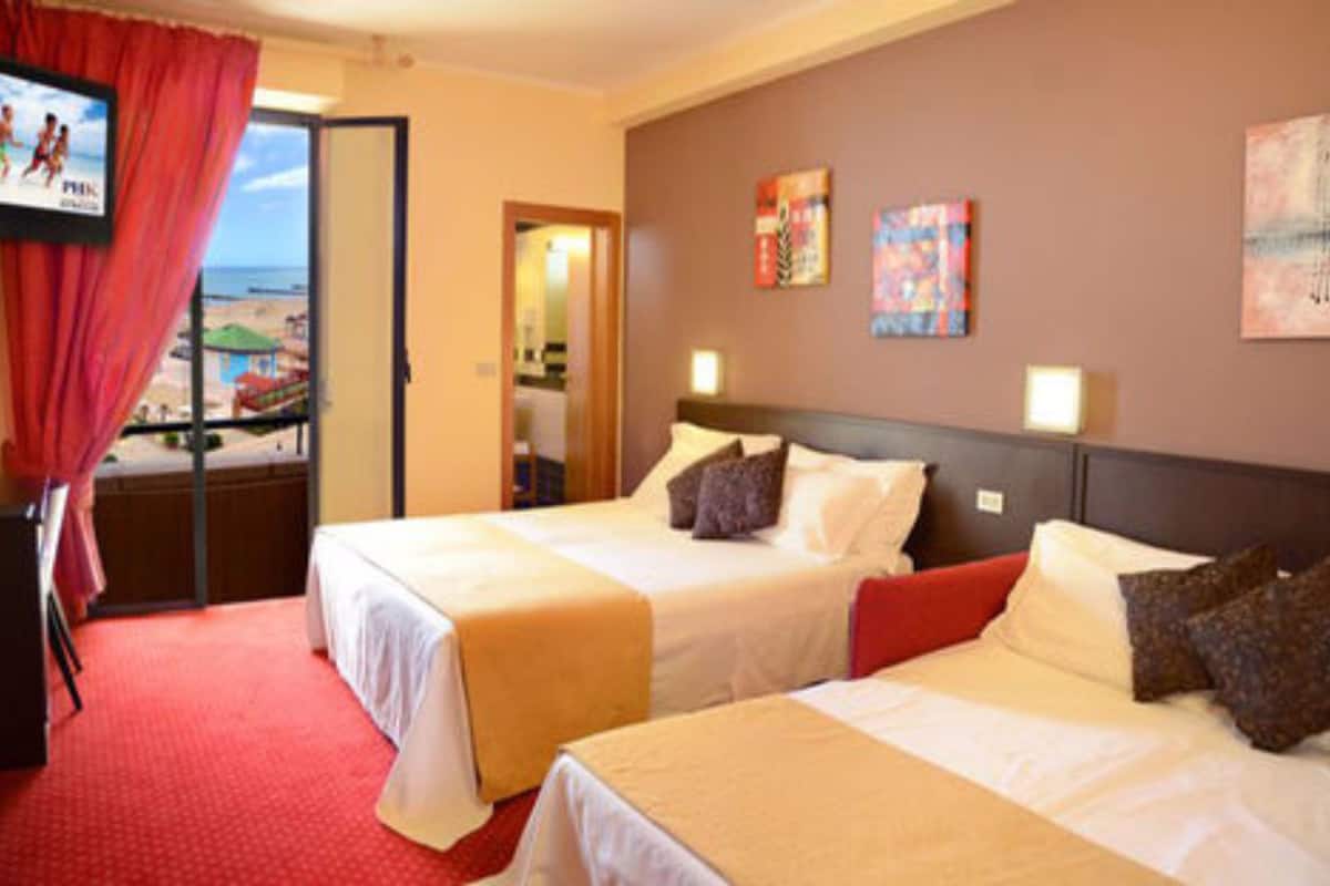 A hotel room with two beds, a TV, and artwork on the walls.