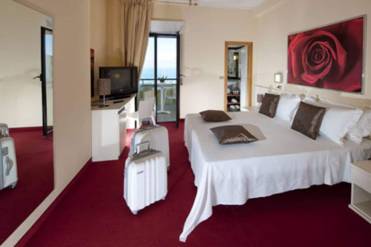 A hotel room with a large bed, a desk, a television, and a view of the outdoors.