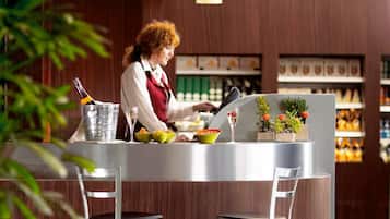 Un espace bar moderne avec un comptoir, deux tabourets et une personne qui prépare des boissons.