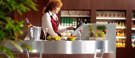 A modern bar area with a bar counter, two stools, and a person preparing drinks.