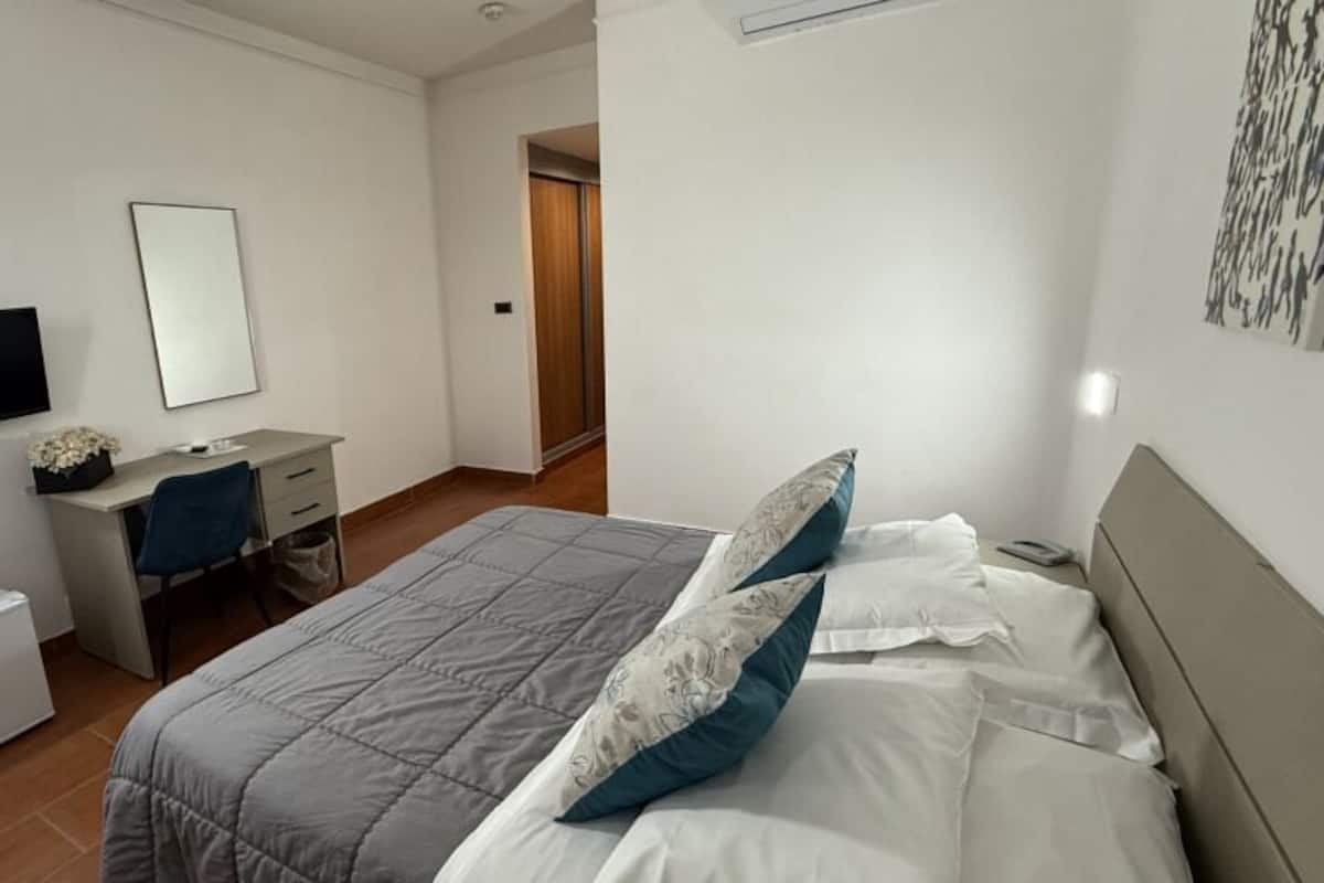 A bedroom with a bed, a desk, a television, and a wardrobe.