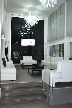 Ein stilvoller Wohnbereich mit weißen Sofas, einem Glastisch und einem großen Fernsehbildschirm.