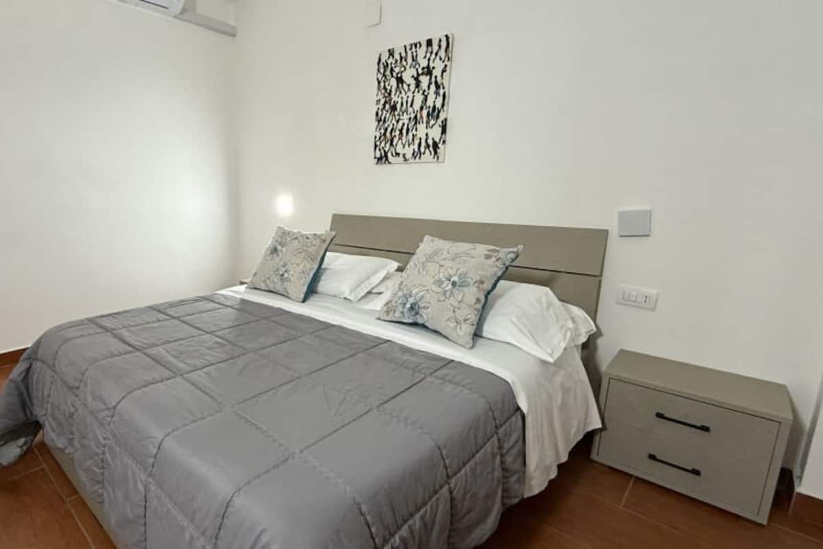 A bedroom with a bed, nightstand, and a door.