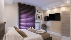Un dormitorio moderno con una cama grande, un televisor de pantalla plana y una ventana con persianas.