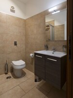 Un baño con inodoro, lavamanos y espejo.
