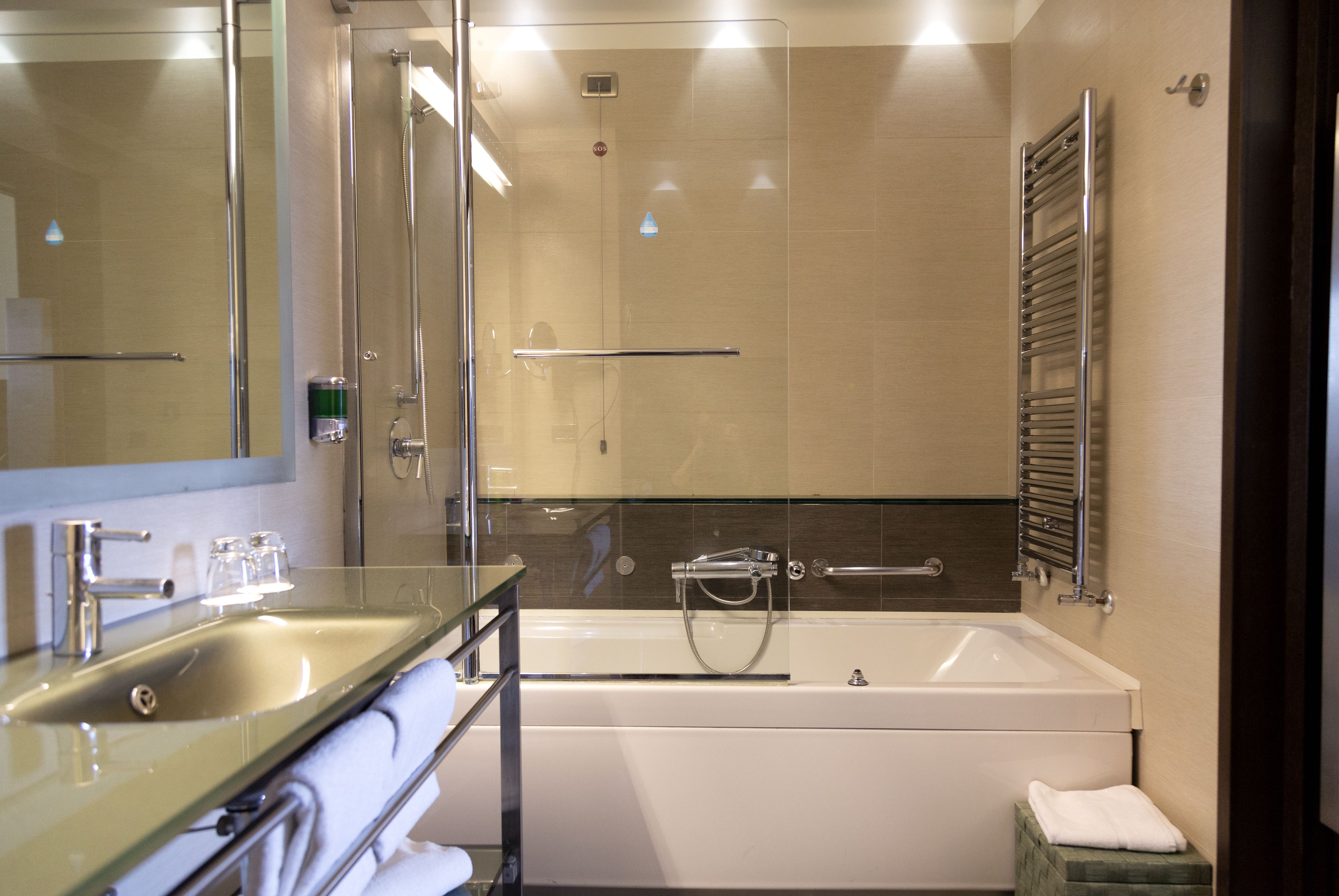 Une salle de bain moderne dotée d’une douche à parois de verre, d’une baignoire et d’un meuble-lavabo avec un évier et un porte-serviettes.